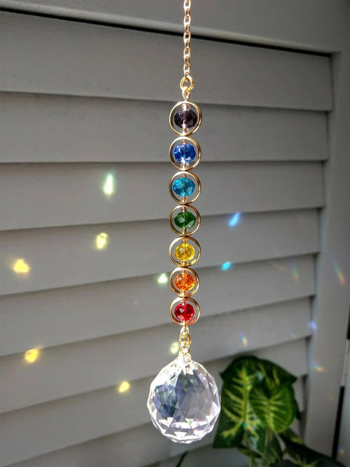 Suncatcher de cristales multicolor frente a una ventana con destellos de luz