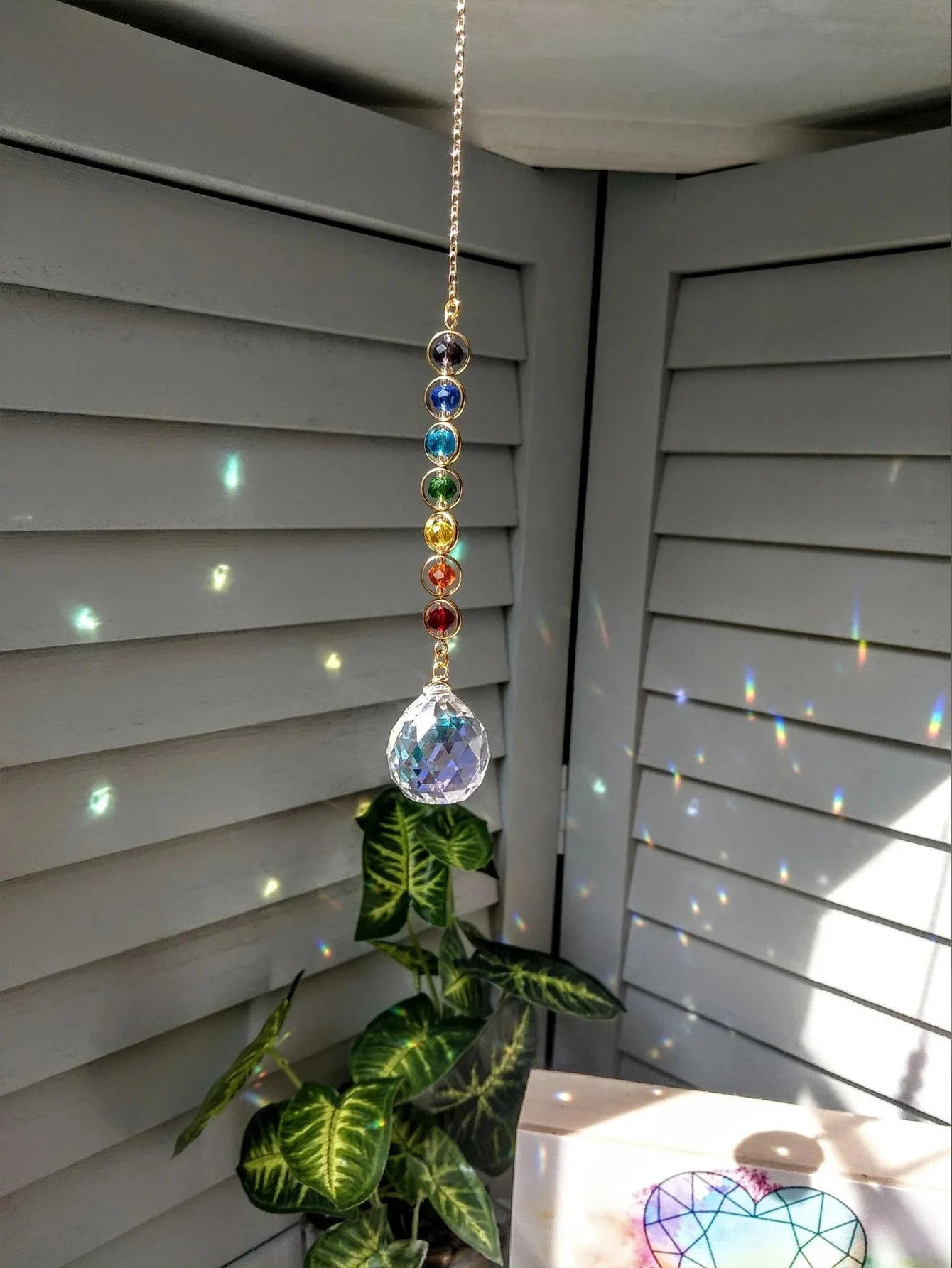 Suncatcher colgado junto a plantas proyectando reflejos de colores