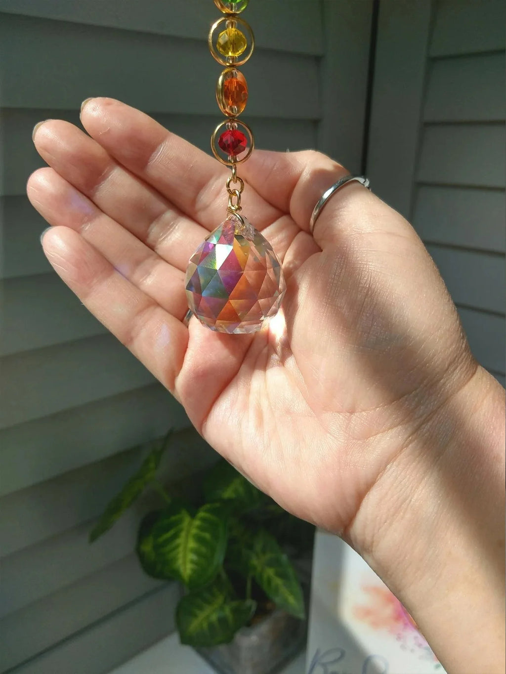 Detalle del prisma facetado del suncatcher sostenido en una mano